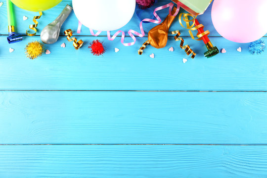 Minimal style composition with different pastel color air balloons with streamer ribbons and other chilldren birthday party attributes on bright background. Top view, close up, flat lay, copy space.