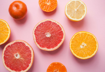 Flat lay of cut ripe juicy grapefruit, lemon and orange on pink background. Flat lay style.