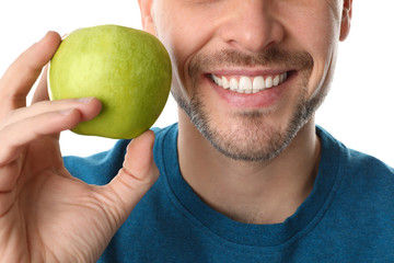 Man with perfect teeth and green apple on white background, closeup