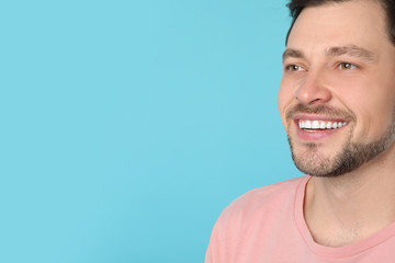 Smiling man with perfect teeth on color background. Space for text