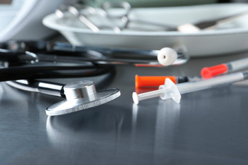 Stethoscope and syringes on grey table. Medical objects