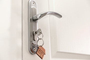 Naklejka premium Key with house-shaped trinket in door lock, closeup. Space for text
