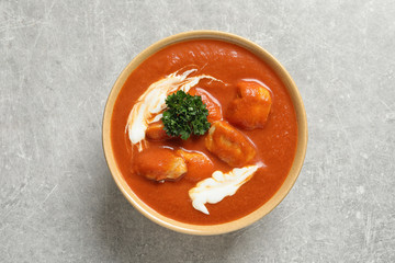 Bowl of delicious butter chicken on grey background, top view. Traditional indian Murgh Makhani