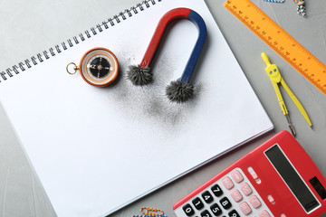 Notebook, compass and magnet with iron powder on table, flat lay composition. Space for text