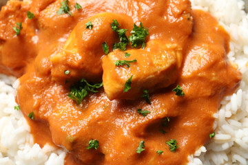 Delicious butter chicken with rice as background, closeup