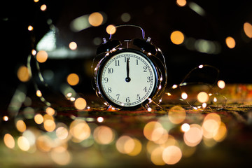 Obraz na płótnie Canvas alarm clock on the eve of the holiday shrouded in garland