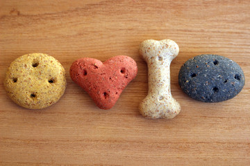 Differently shaped and coloured dog biscuits on a wooden background