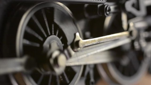 Minature electric powered model steam locomotive driving wheels and connecting rods start turning then accelerate before coming to a stop.