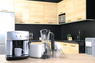 Modern domestic appliances on wooden table in kitchen. Space for text