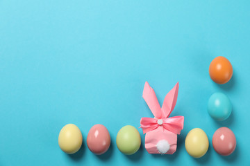 Flat lay composition of Easter bunny gift bag and dyed eggs on color background. Space for text
