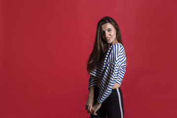Studio shot of a lovely beautiful woman isolated against an empty red studio wall.