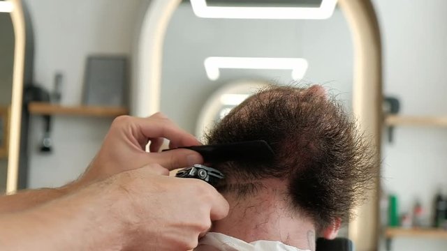 Close up barber shaving beard on neck with electric trimmer at barbershop