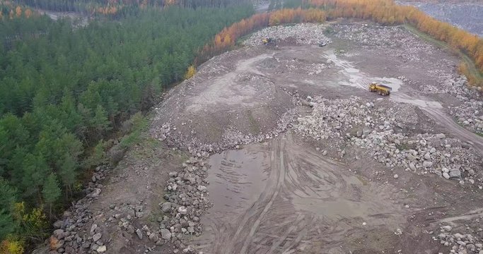 Aerial, descending, drone shot, of a dumb truck, driving towards a Crawler Excavators, Volvo EC380EL, digging up soil, in Pohjanmaa, Finland