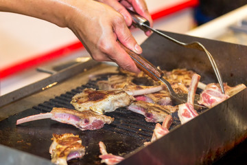 hand of man cooking delicious bone meat or barbecue steak with turner on hot pan