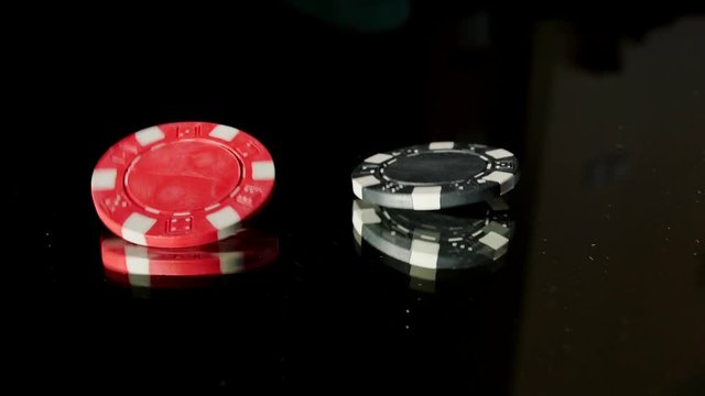 Poker Chips Spinning on Glass Table on Black Background Slow Motion