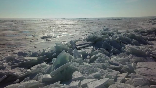 Frozen icy waves pushed up against a dock in the middle of frozen lake Erie in Kingsville, Ontario. Drone sweeping shot.