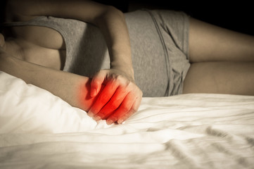 Female suffering from elbow pain on bed.
