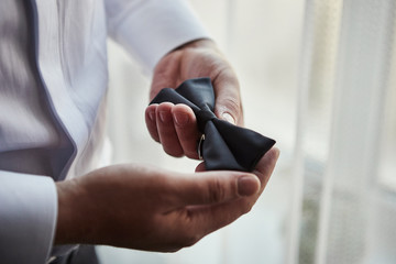 businessman putting on  bow tie,man butterfly clothes,groom getting ready in the morning before wedding ceremony