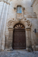 Fototapeta na wymiar Monopoli, Puglia, Italy - View of street in Monopoli, Apulia. Italian spirit of southern Italy. Beautiful baroque door 