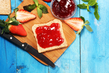 Toast bread with homemade strawberry jam or marmalade on table served with butter for breakfast or brunch