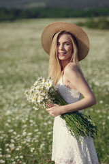 Beautiful woman enjoying field of spring daisy