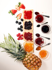 assortment of jams, seasonal berries, plums, mint and fruits in glass jar