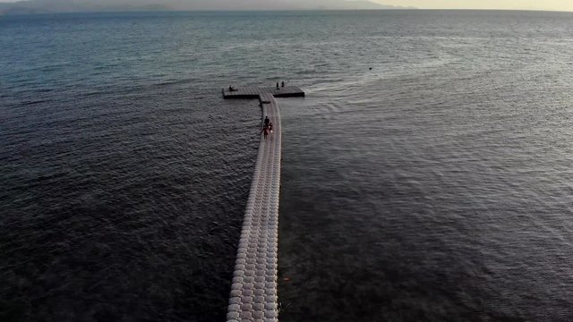 Drone shot of a floating pier with people walking on it