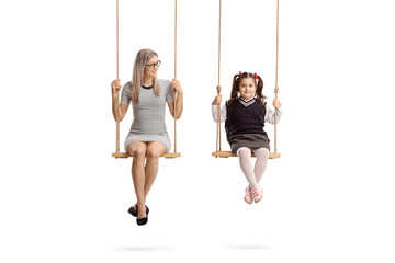 Young woman and little schoolgirl sitting on swing