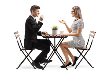 Young man in a suit drinking cofee and sitting at a table with a young woman