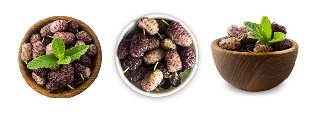 Set of mulberries. Mulberries in a wooden bowl with copy space for text. Black and purple mulberry on white background. Ripe and tasty mulberry isolated on white background. Top view.