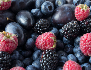 Ripe blackberries, blueberries, plums and raspberries. Mix berries and fruits. Top view. Background berries and fruits. Various fresh summer fruits. Black-blue and pink food.