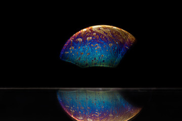 Reflection of a bubble in rainbow colors on a black background.