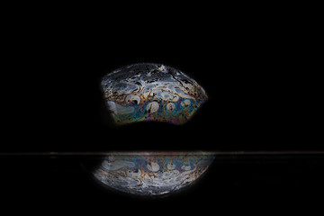 Reflection of a bubble in rainbow colors on a black background.