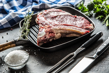 Rib eye steak in grill pan with herbs salt pepper fork and knife