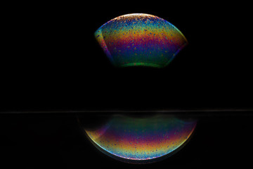 Reflection of a bubble in rainbow colors on a black background.
