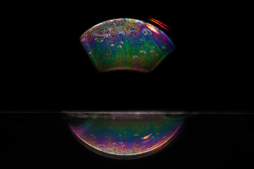 Reflection of a bubble in rainbow colors on a black background.