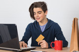 young man with credit card and laptop buying online