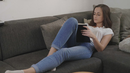 Obraz premium Young woman relaxes in the living room while reading a book