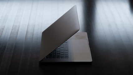 Grey modern laptop on a black table, beautiful light.