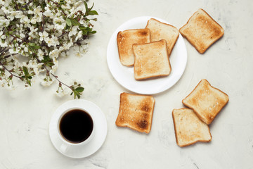 White Cup with Black Coffee, Toast, Jem and Spring Flowers on the Light Stone Background. The concept of a Healthy Breakfast. Flat lay, top view