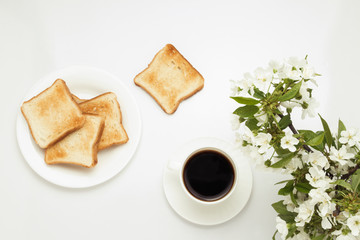Toast, coffee and blossoming cherry branches on a white background.