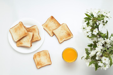Toast, orange juice and blossoming cherry branches on a white background.
