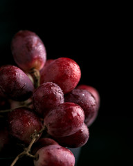 Purple grapes with water drops, grape juice in a glass jar, dark picture. Selected focus, macro.