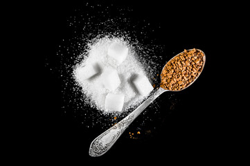 Teaspoon with instant coffee and heap of sugar on black. Top view.