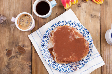 Two cups of aromatic coffee and pancakes with cream. Breakfast for two on a wooden background. Free space for text.