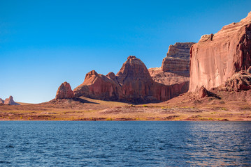 Fototapeta na wymiar Red orange and yellow sandstone canyons and cliffs are naturally complemented by deep shades of blue. A bathtub ring is visible from the rising and then falling water levels of Lake Powell, Utah. 