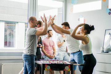happy managers playing table football at office and having fun together