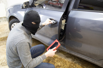 The hijacker tries to break into the car with a scanner. Code grabber . Car thief, car theft.