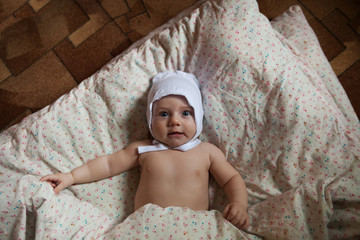Naked  child of three months lying on   blanket.