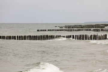 Fototapeta na wymiar Wooden breakwaters protects the Baltic sea coast